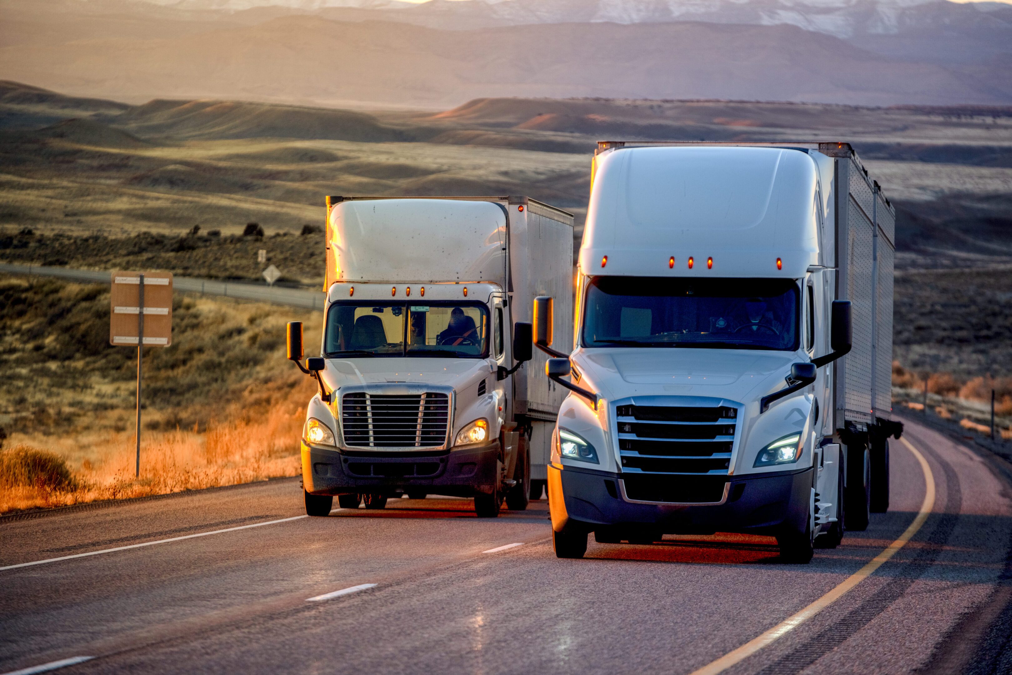 Two trucks driving on a highway.