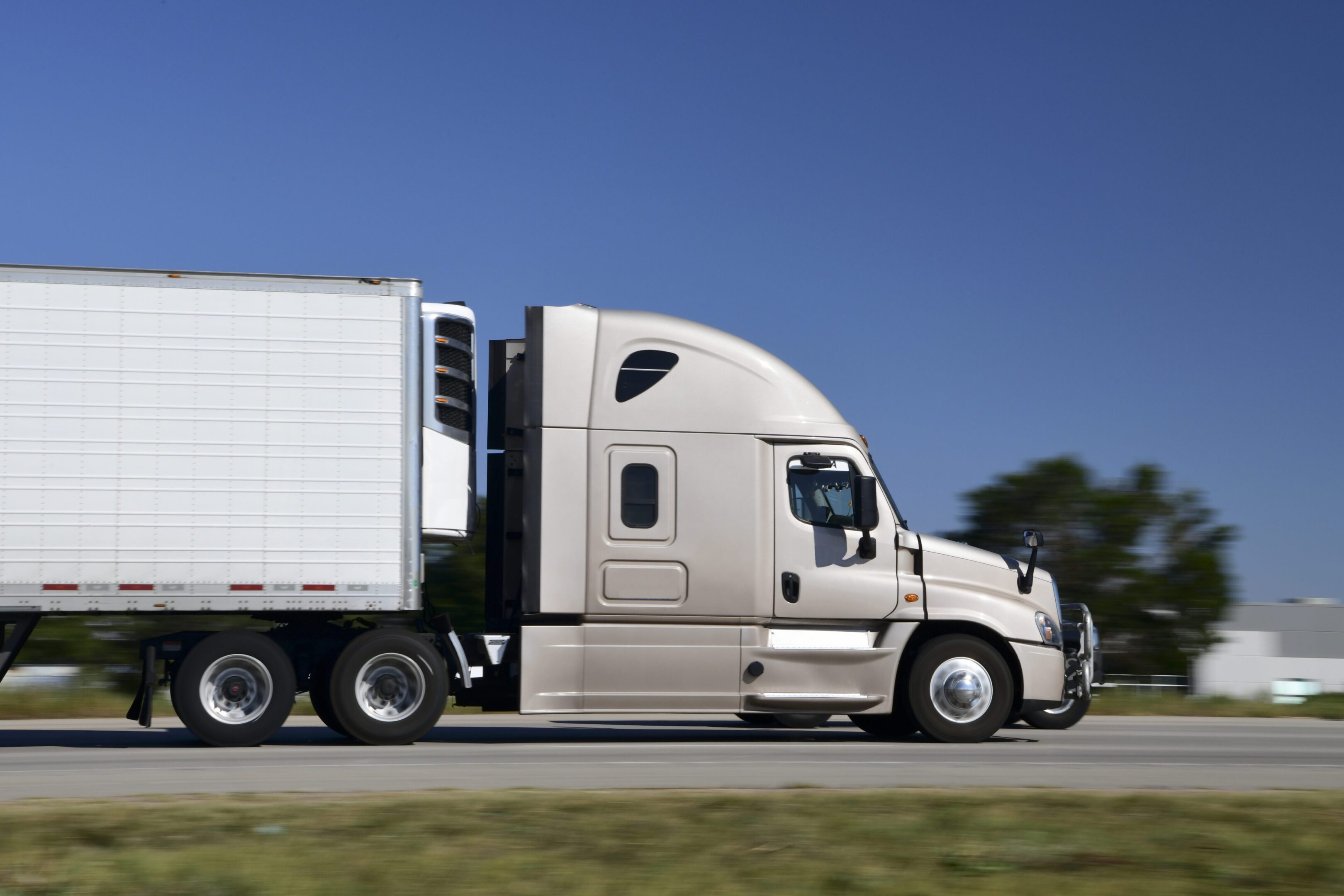 White semi-truck driving on a highway.