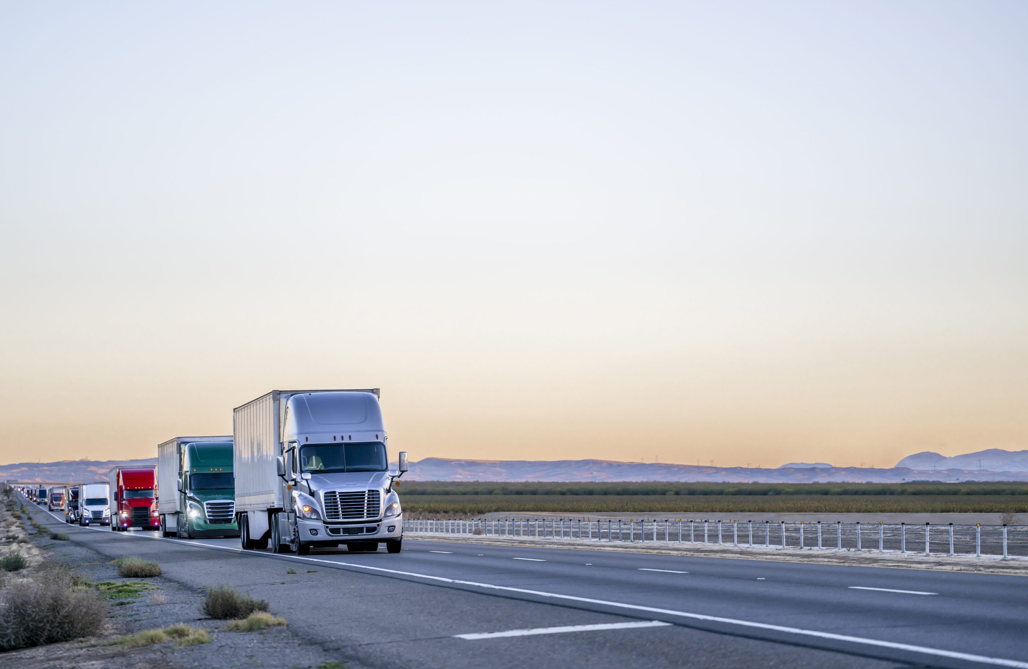 Trucks driving on a desert highway.
